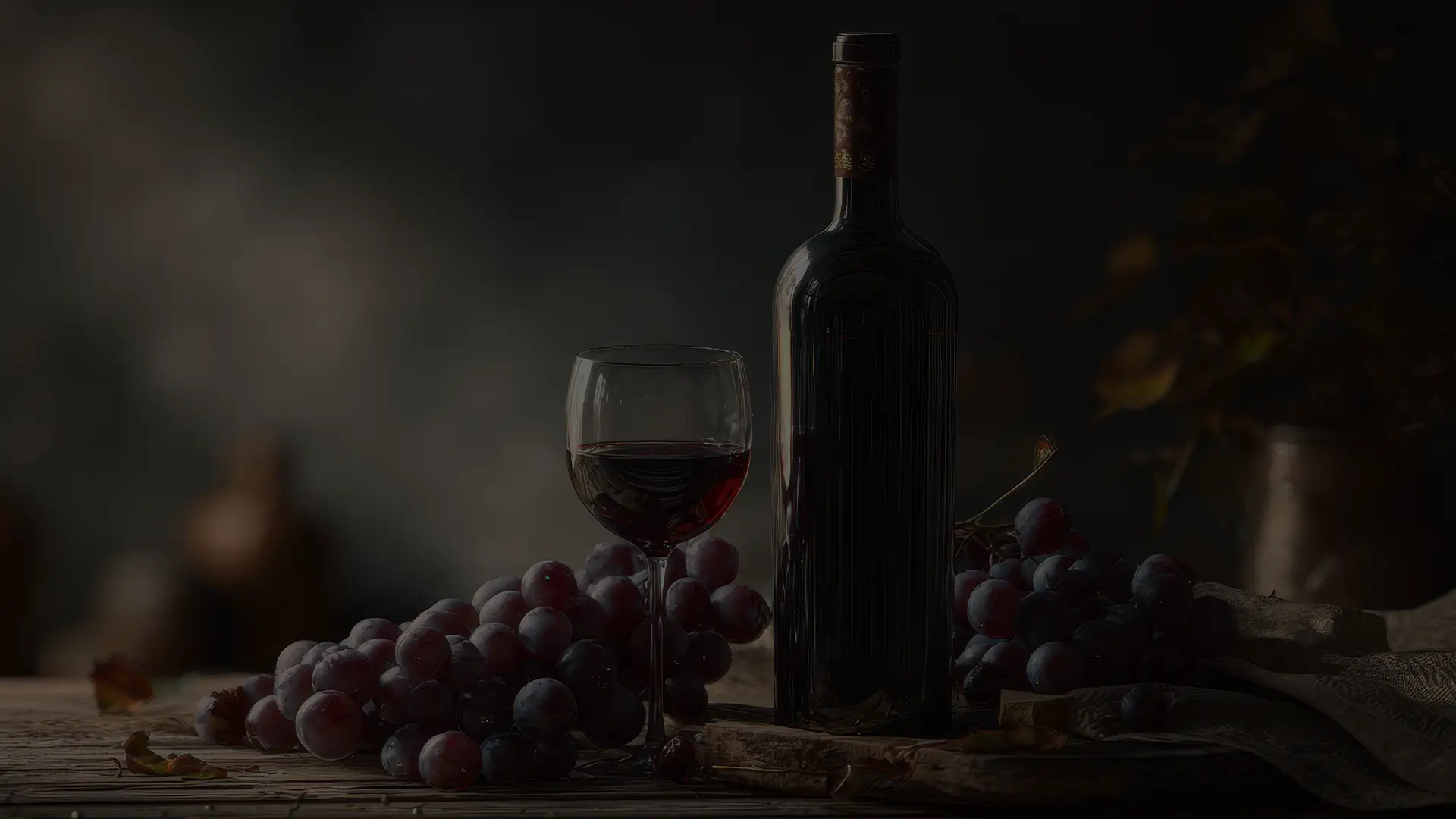 Weinflasche, Weinglas und dunkle Trauben auf einem Tisch